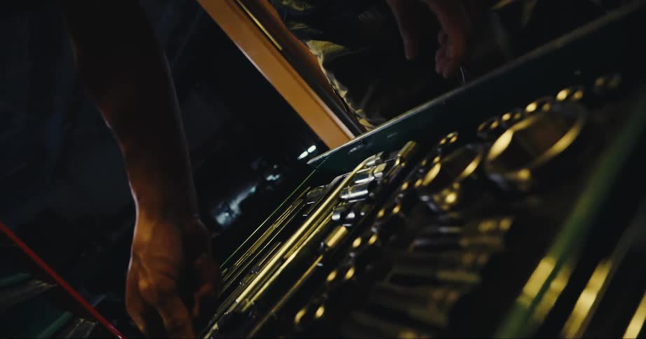 A man is opening a tool chest and removing tools in a closed garage during the day
