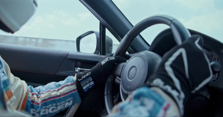 Race car driver steers car under cloudy sky