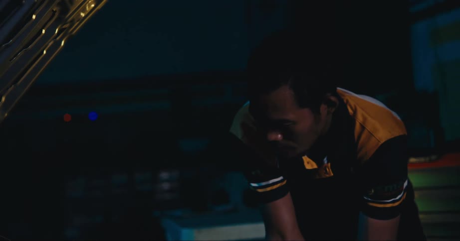 Two men are working on a vehicle in a garage at night