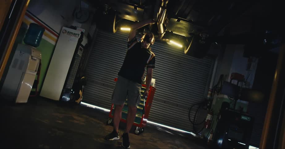 A mechanic examines a vehicle on a lift