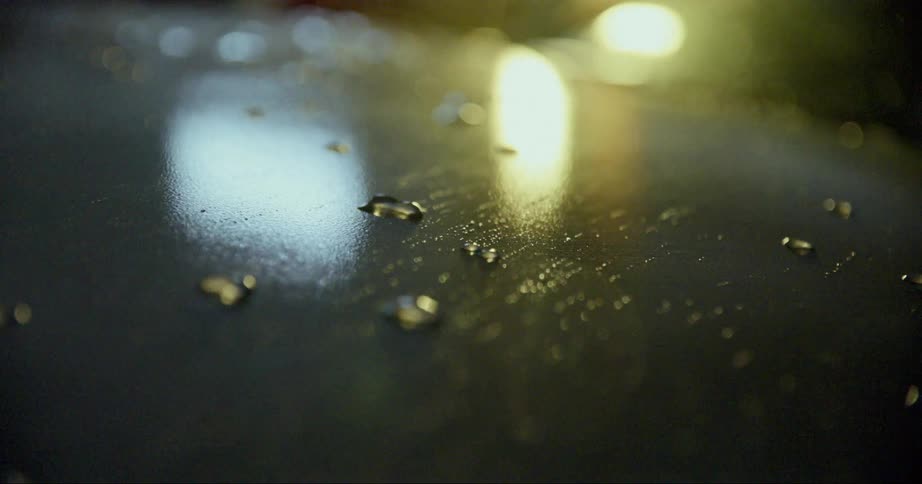 Water droplets are shaking on a shiny surface reflecting light