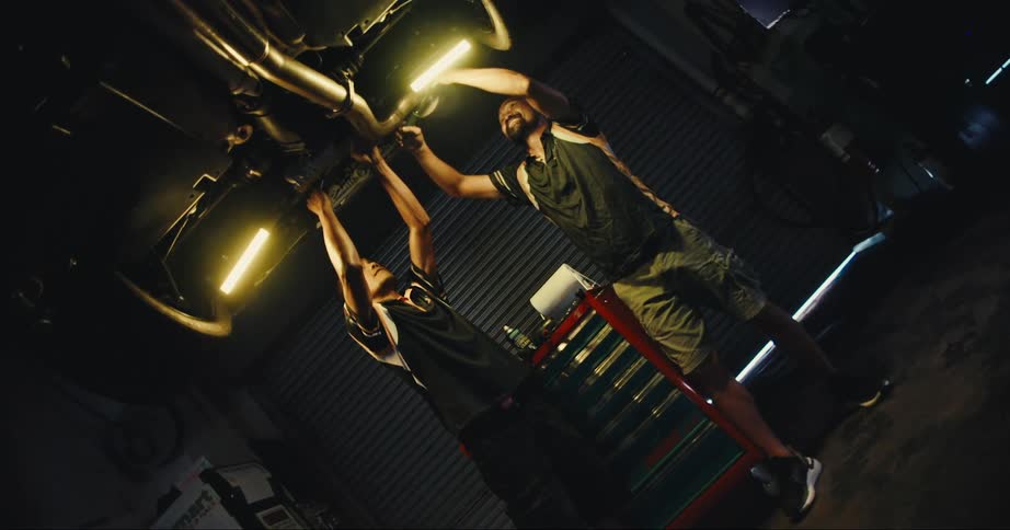 Two mechanics work on a vehicle on a lift