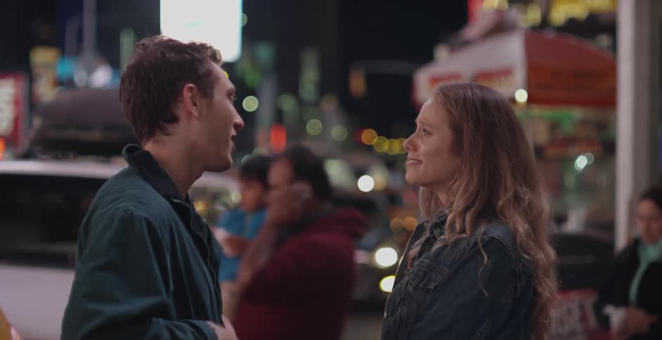 A man and woman talking in a city at night