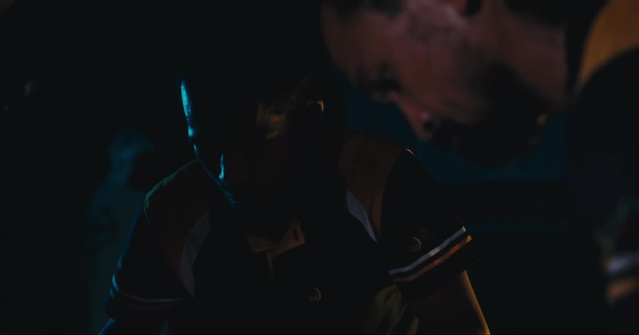 Two men look under the hood of a car at night