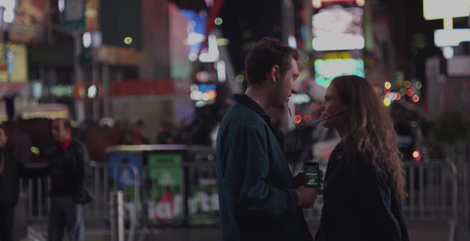 A man and women talk on a city street at night