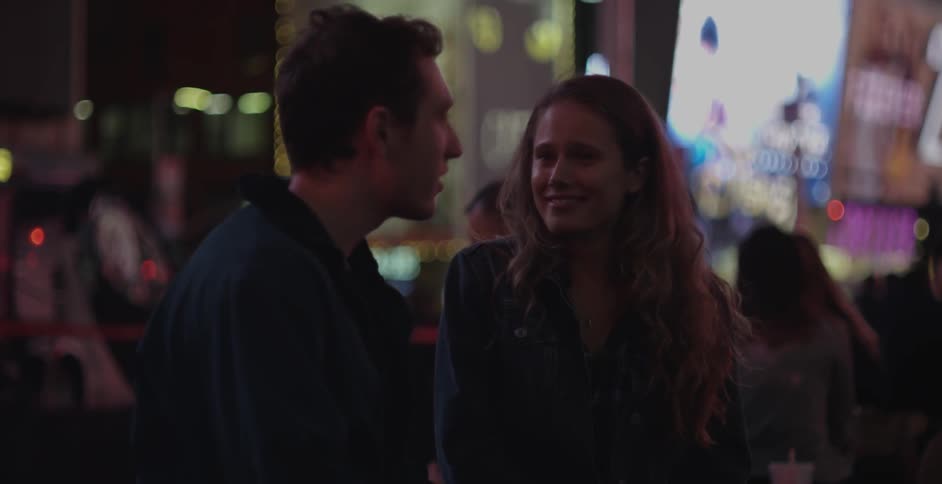A man and woman talk on a crowded street