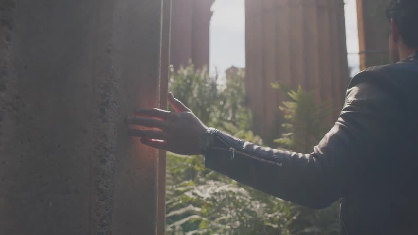 A man walks past huge pillars in the forest