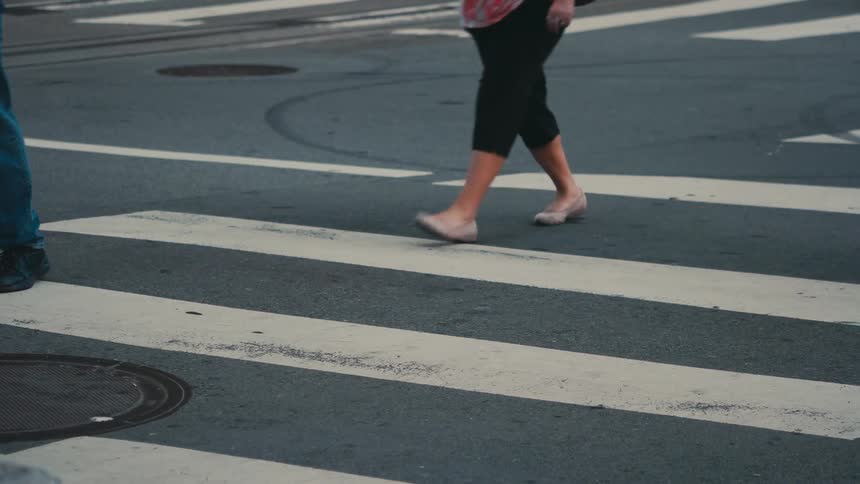 People are walking across a crosswalk on a busy street