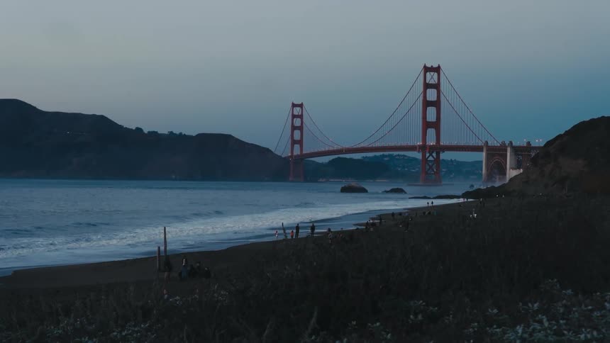 People are all over the beach by the bridge
