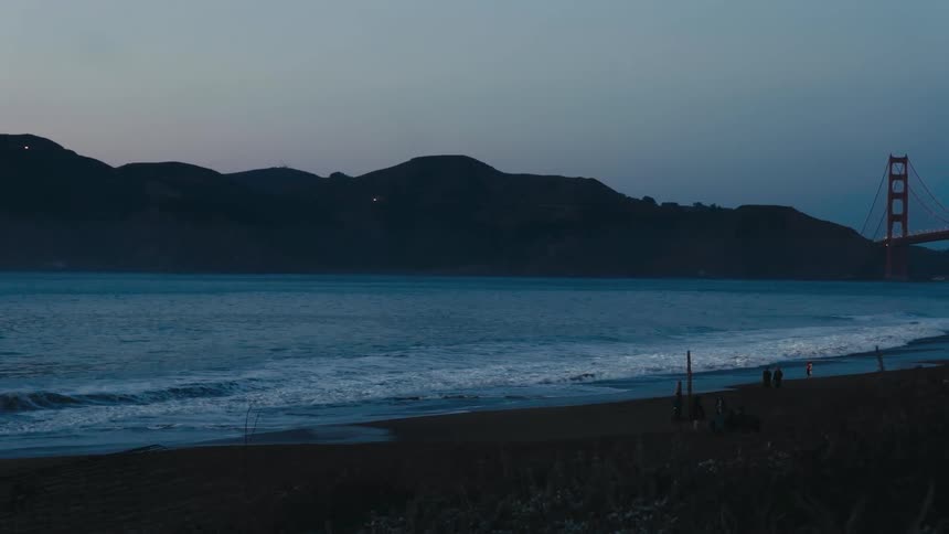 Distant suspension bridge seen from coast at dusk