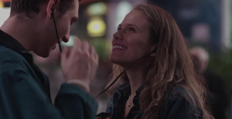 Man and woman sharing earphones and laughing