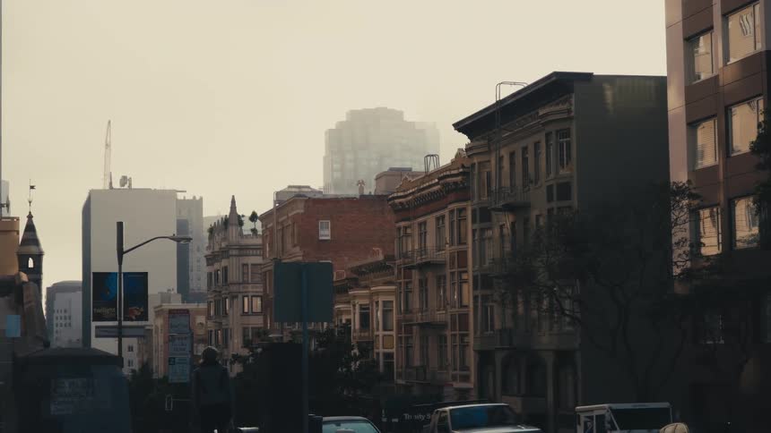 A smoggy downtown city area with cars people and bulidings