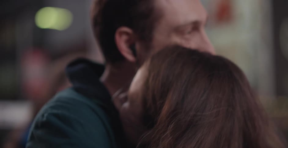 A man kisses a woman on the forehead and hugs her
