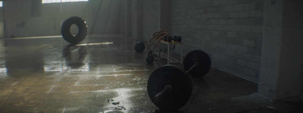 Weights and fitness equipment on the wet floor of a dimly lit gym