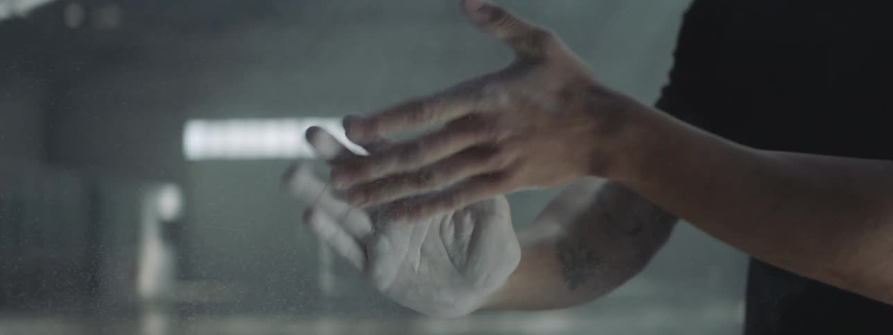 A man rubs his hands together to shake off a white powder while walking through a room with cement falls