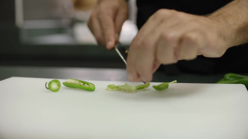 A man uses a knife to remove the seeds from a sliced pepper