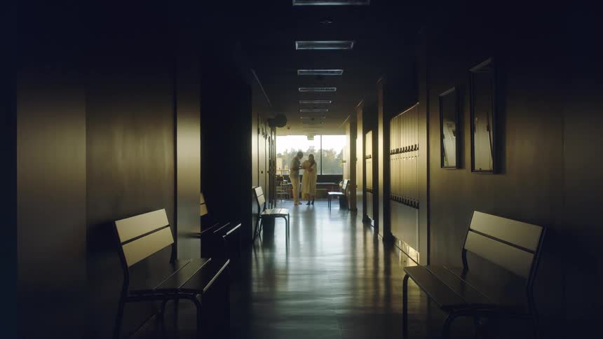 Hospital attendant helps patient walk through hospital corridor