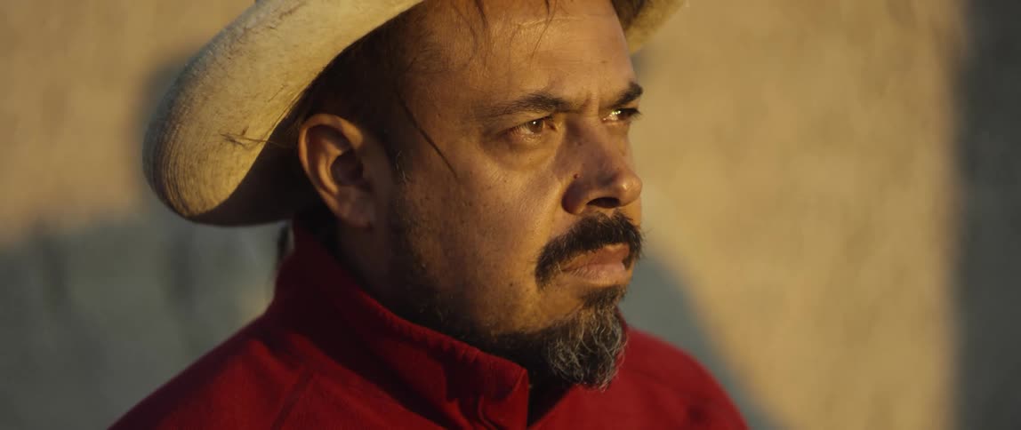 A man with a hat staring off into the distance with sunlight on his face