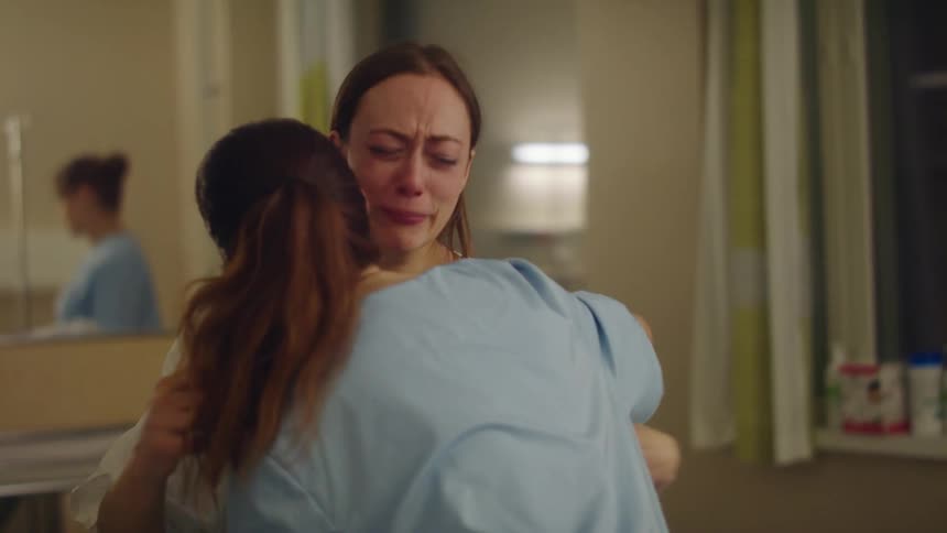 Two women crying and hugging at a hospital