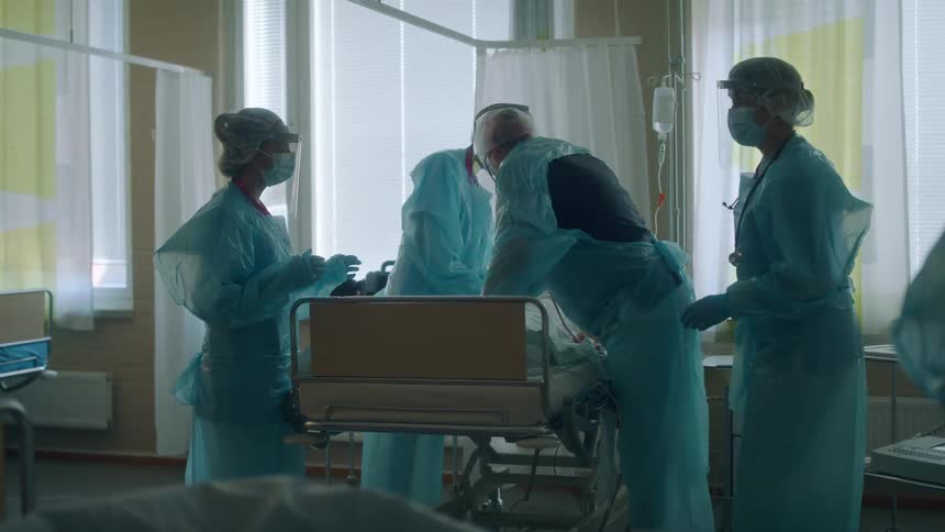Nurses are tending to patients in beds inside a hospital during the daytime