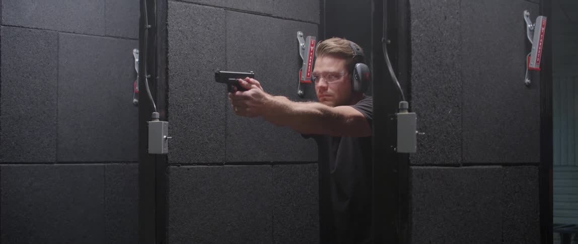 A man in a gun range shoots a gun