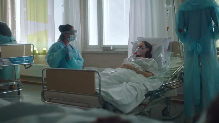 A patient surrounded by talking doctors in a hospital room