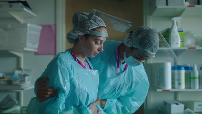 A doctor walks over to a colleague and consoles her