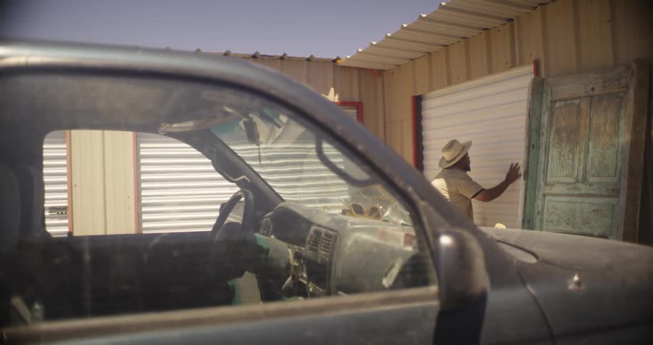 Man gets out of a dirty truck and enters a storage unit