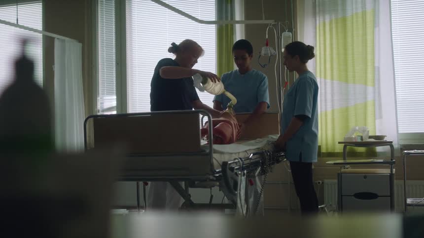 A nurse demonstrates how to bag a patient and squeeze oxygen to them on a dummy in a hospital bed