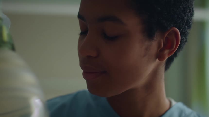 A nurse is looking down while caring for a patient in hospital setting
