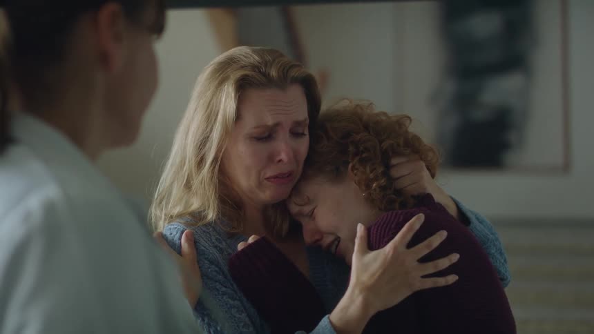 Two women crying at a hospital in front of a doctor