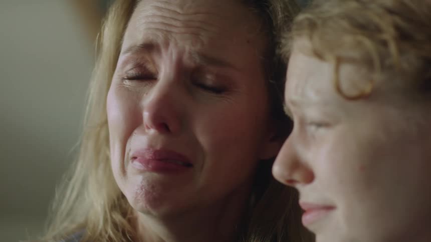 Two women are looking ahead and crying and they comfort each other