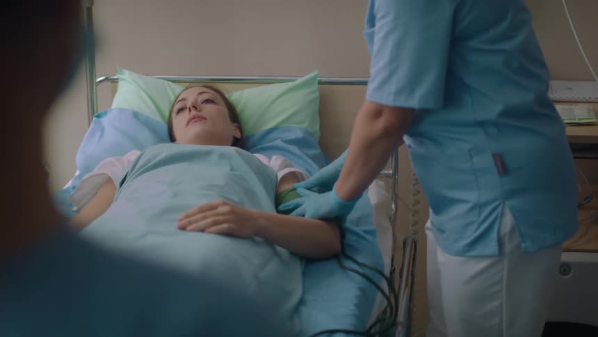 A nurse taking a patients blood pressure in a hospital room