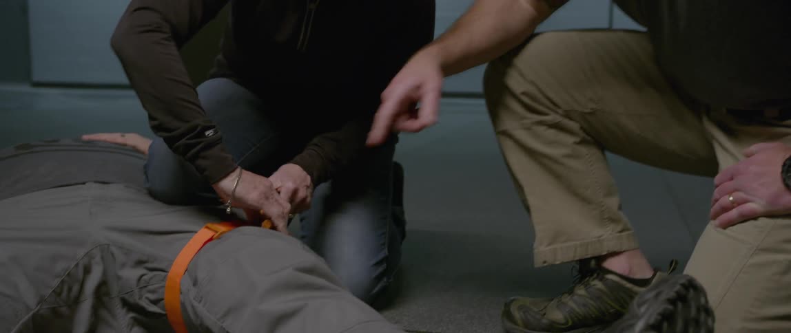 A woman ties a tourniquet on a man
