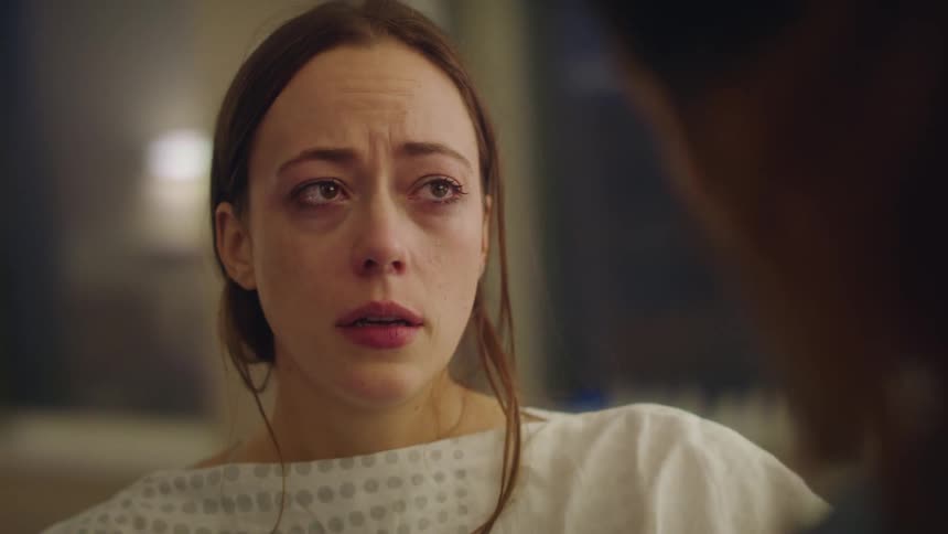A woman is being helped by a nurse and she looks very sad