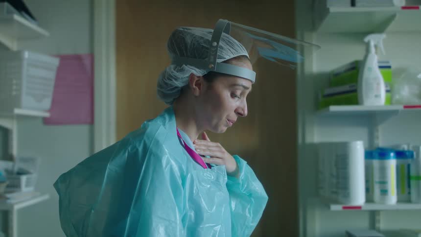 Doctor wearing protective clothes calming herslef down inside a room