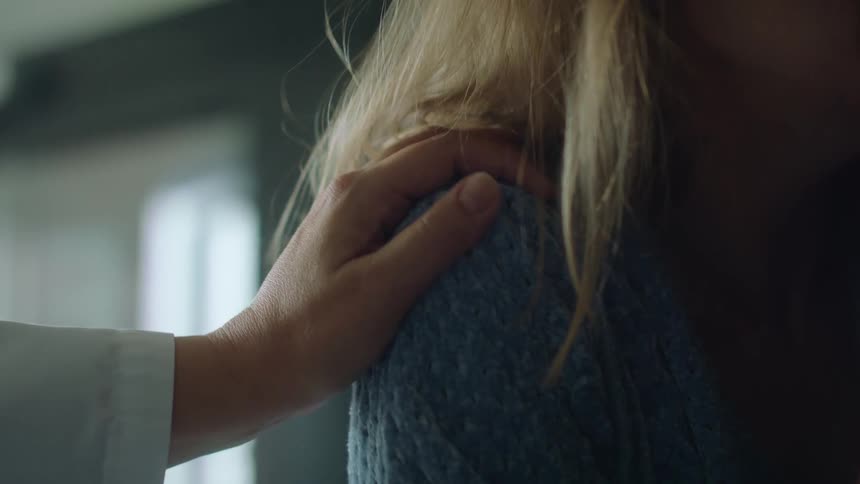 A person touches the shoulder of a crying woman in consolation