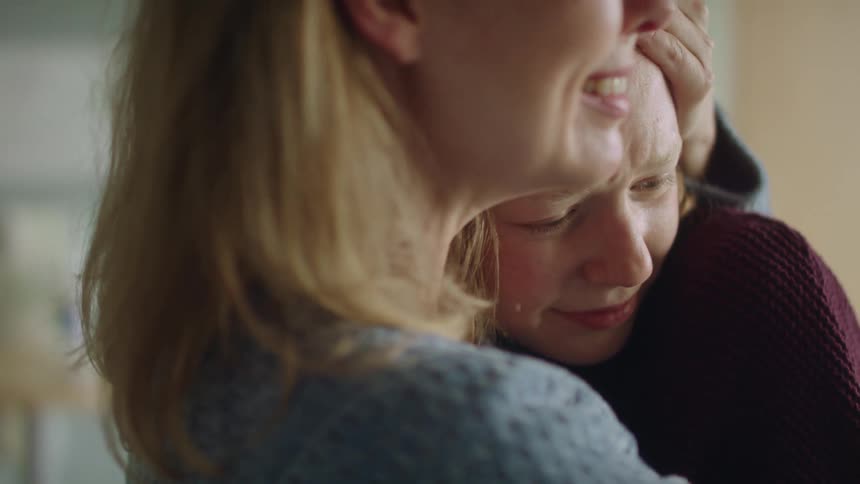 A mother is hugging her crying daughter