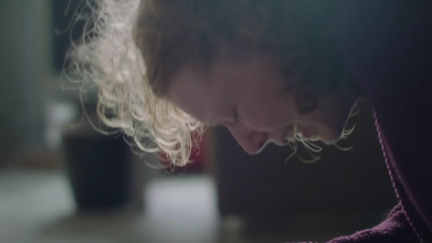 A young woman cries while kneeling on the floor