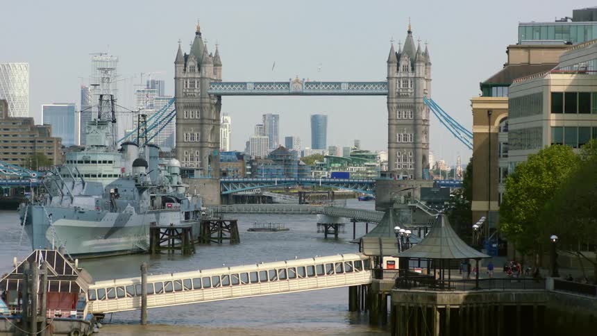 A navy ship is docked near the tower bridge in london