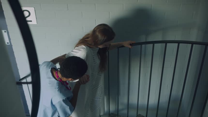 Nurse wearing a face mask helping a patient walk up the stairs slowly