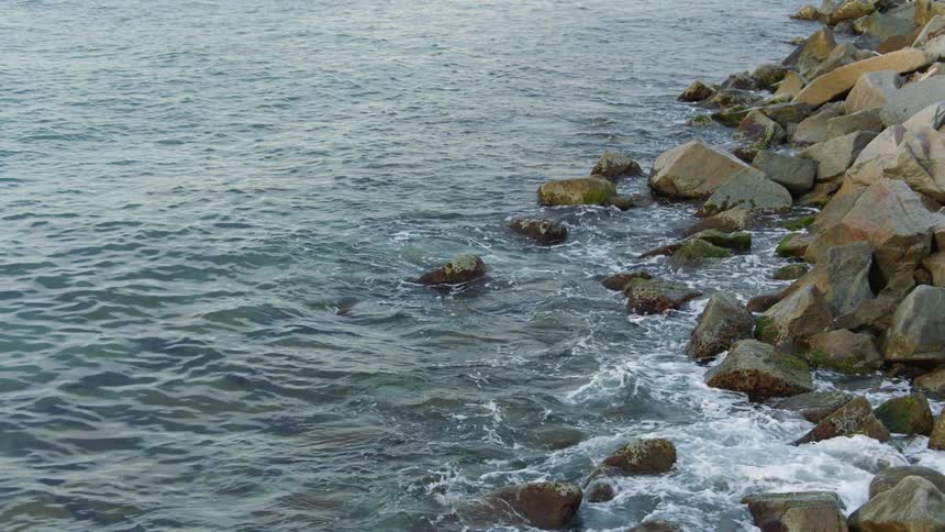Small ocean waves crashing on the rocks in the coast at morning