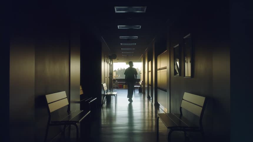 A person walking quickly down a hallway looking around the building