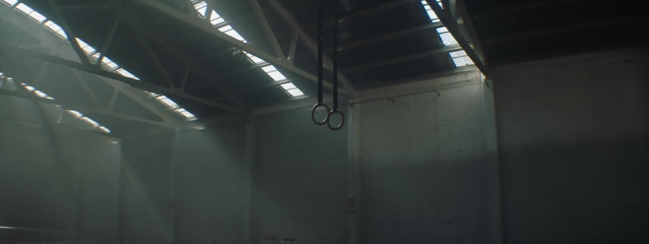 A gym with gymnastic rings with a wall in the background