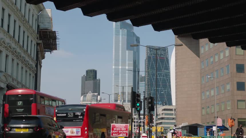 Red busses and cars driving on city highway with high rise buildings in the background