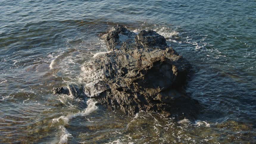 Aerial view of waves splashing against a rock formation