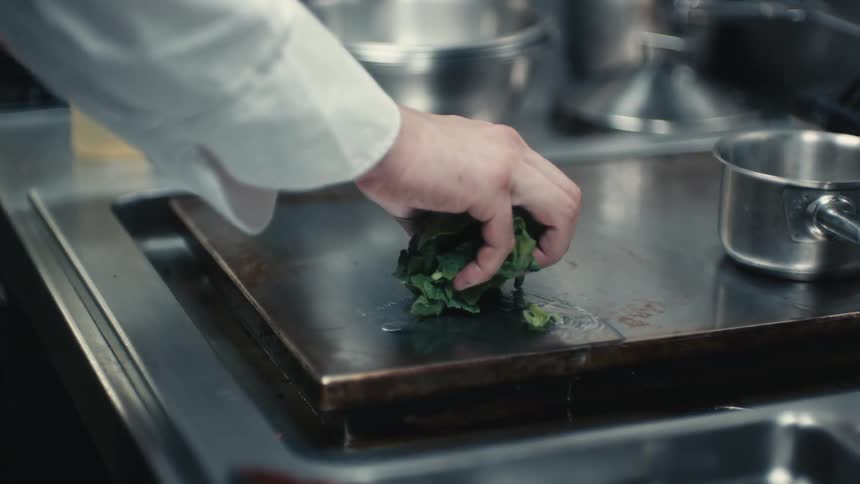 A chef places vegetables on the hot surface to cook