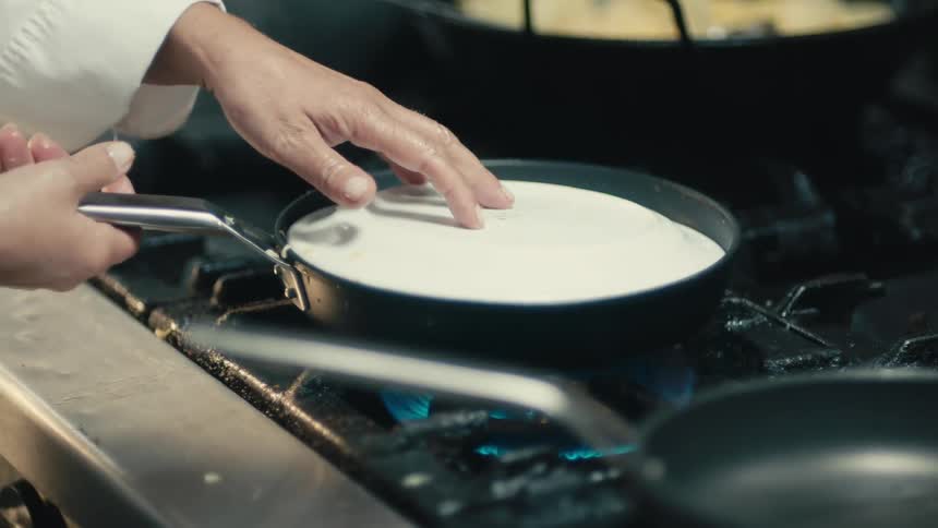 Chef inverts gas stove cooked egg dish onto plate from skillet