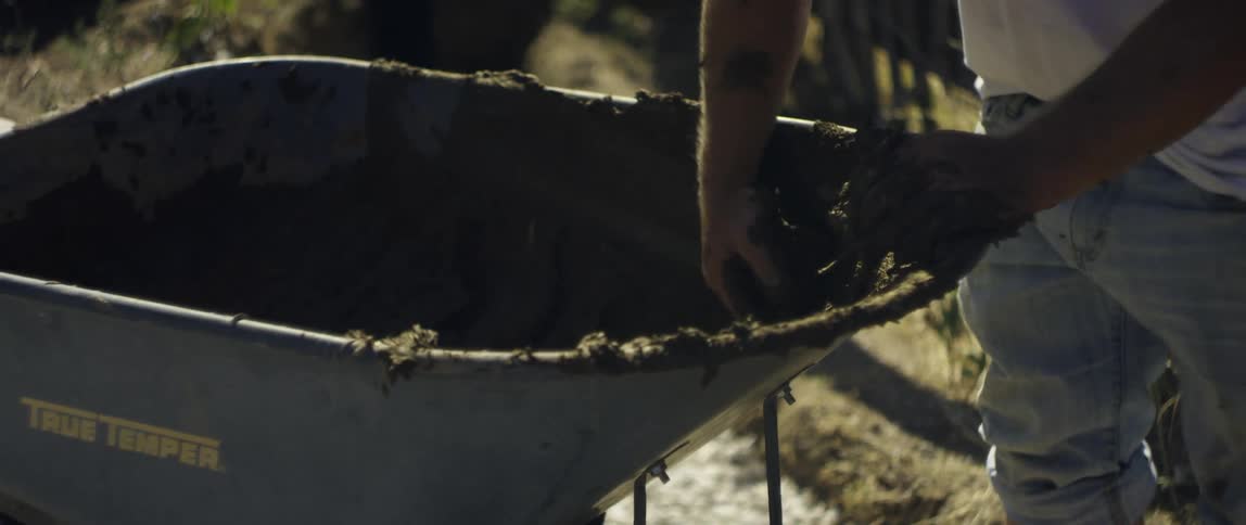 An employee moving dirt from a wheel barrow