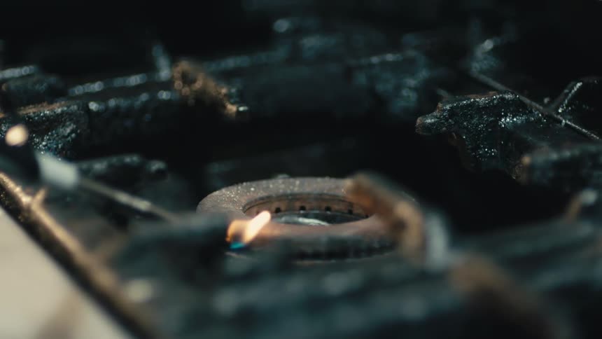 Gas stove top range burner firing up with a lighter